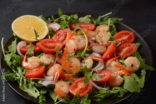 Fresh salad plate with shrimps, onions, lemon, tomatoes and mixed greens (arugula, mesclun, )