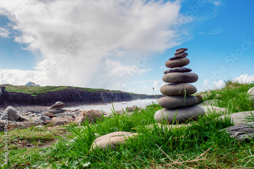 Pile of rocks stack on each over in nature environment. Warm sunny day, cloudy sky. Balance, patience and zen concept
