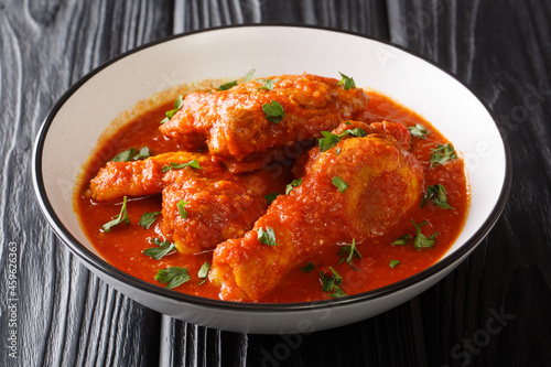 Authentic Ayam Masak Merah Recipe made with chicken pieces that are doused in a spicy tomato sauce close-up in a bowl on the table. Horizontal photo