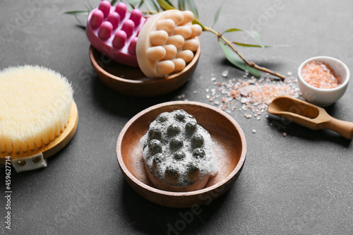 Bowl with massage soap bars, brush and sea salt on dark background