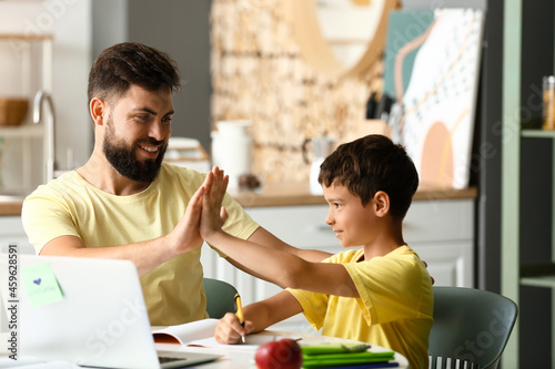 Little boy with his father doing lessons at home