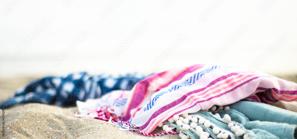 Bright colored towels on the beach in boho style. - obrazy, fototapety, plakaty 