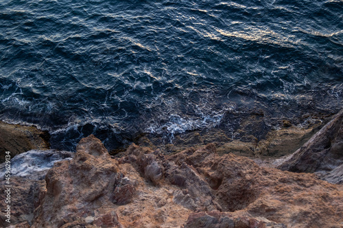 The dark blue sea collides with the rock. Top view © konkovva