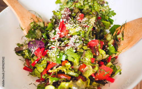 Close up - Woman hands Stirring A Bowl Of Fresh Vegetable Salad with wooden spoon.