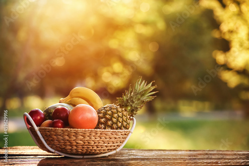 Fototapeta Naklejka Na Ścianę i Meble -  Wicker basket with fresh fruits on table outdoors