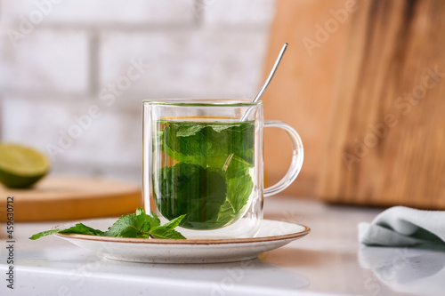 Φωτογραφία Glass cup of tasty mint tea on table in kitchen, closeup