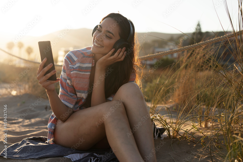  Happy young woman relaxing on the sandy beach. Beautiful woman listening the music