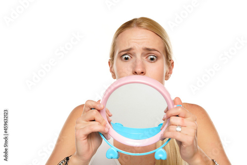 portrait of a young unhappy woman looking her self in the mirror