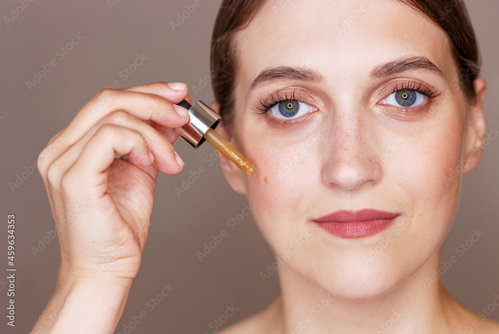 Portrait of young woman holding dropper with serum, skin care concept. Portrait of young woman holding dropper with serum, skin care concept.