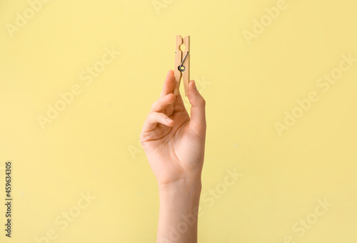 Woman holding clothespin on yellow background