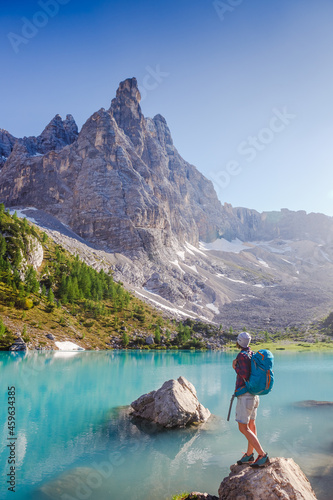 Amazing view of Sorapis lake (Lago di Sorapis) with traveler girl on the rock looking on the mountain Dolomites, Italy
