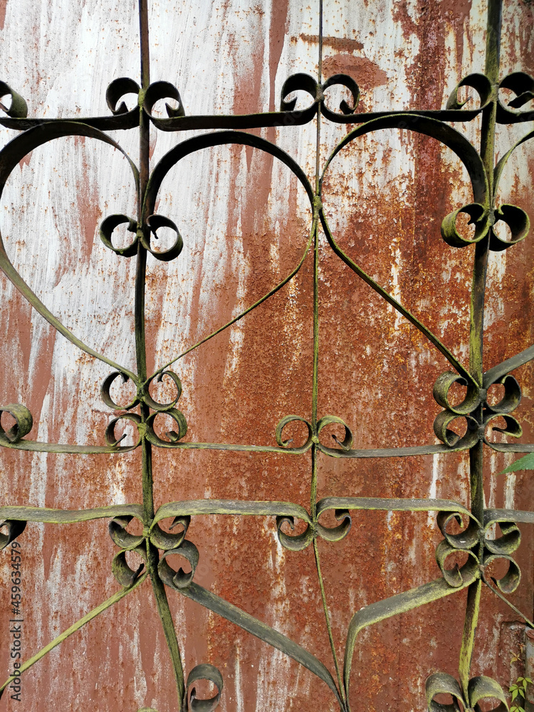texture of an old metal garage wall behind a patterned fence texture of an old metal garage wall behind a patterned fence