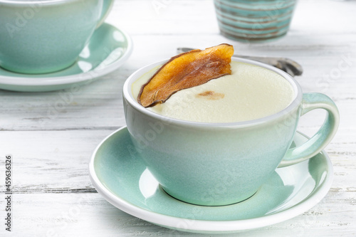 Cup of cappuccino coffee in a blue mug on white wooden background