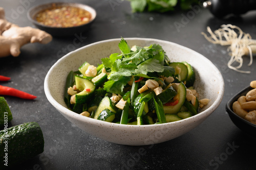 Chinese spicy broken cucumbers salad with cilantro, ginger, pepper chili, black vinegar on Asian cuisine. Spicy cucumbers. Popular cold Chinese appetizer. Close up. photo