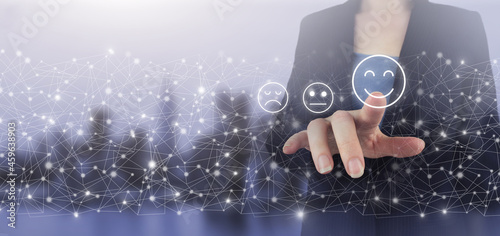 Review, Rating,Satisfaction. Hand touch digital screen hologram Smiley Face sign on city light blurred background. Business satisfaction survey. Smiley Face Rating for a Satisfaction Survey