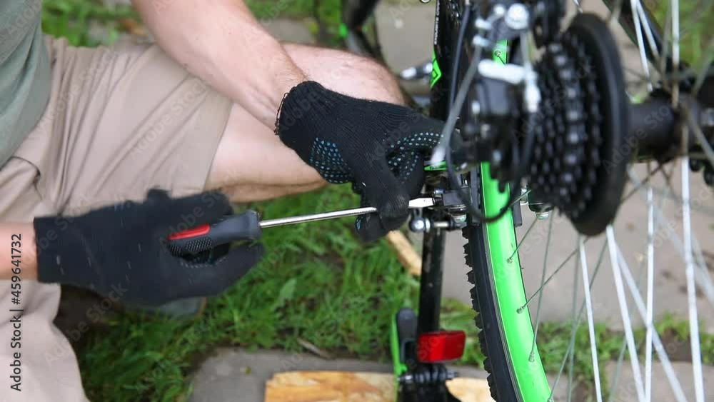Bike mechanic man repairs bicycle in bicycle repair shop, outdoor. Hand of cyclist bicyclist examines, fixes modern cycle transmission system. Bike maintenance, sport shop concept Bike mechanic man repairs bicycle in bicycle repair shop, outdoor. Hand of cyclist bicyclist examines, fixes modern cycle transmission system. Bike maintenance, sport shop concept
