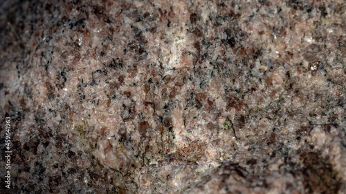 Red granite texture. A variegated, spotted background of red (brown) granite. The stone granite surface of brown-gray color. Surface view of granular igneous rock