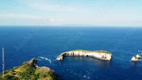 Fly around cliff and rocks over ocean along coast with amazing view on Diamond Beach, Nusa Penida, Bali, Indonesia. High quality 4k aerial footage photo