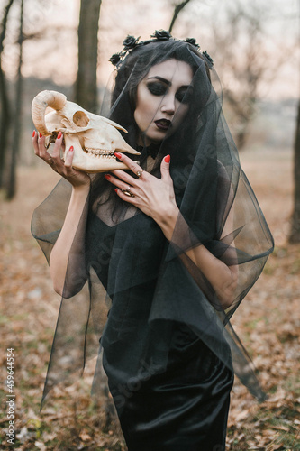 Fotografia Brunette witch girl conjures in the forest conducts rituals with a fantasy skull