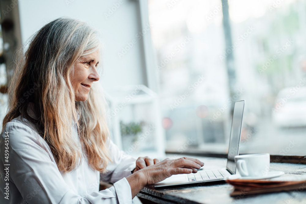 Female freelancer using laptop at table in cafe Female freelancer using laptop at table in cafe