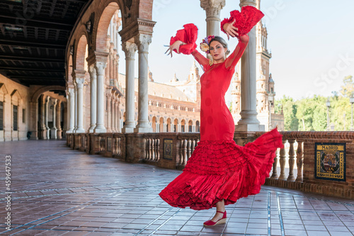 Female flamenco artist dancing with hands raised on walkway at Plaza De Espana, Seville, Spain photo
