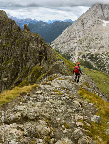 Mountian climber walking on a narrow rocky ridge with helmet and Backpack, ready for climbing as part of the via ferrata Trincee in the italian Dolomites of South Tyrol