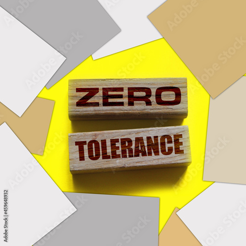 Zero tolerance - words from wooden blocks with letters, severely punishing all unacceptable behaviour, zero tolerance concept, yellow background photo