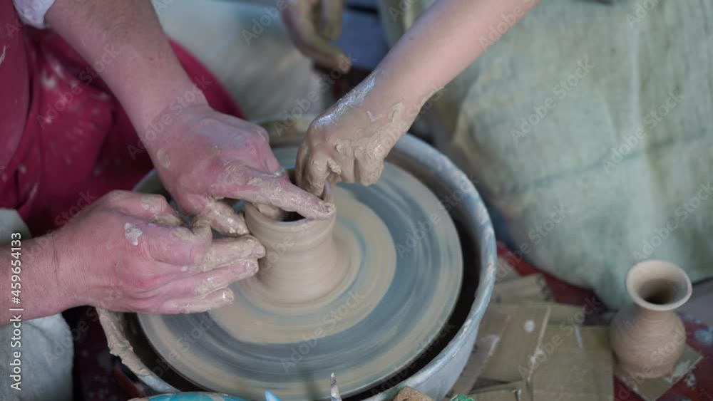 Potter Teaching Pottery Little Girl Man Teaches Child Make Dishes From Clay Work Twisted Potters Wheel. Master Crock. Close up only hands Potter Teaching Pottery Little Girl Man Teaches Child Make Dishes From Clay Work Twisted Potters Wheel. Master Crock. Close up only hands