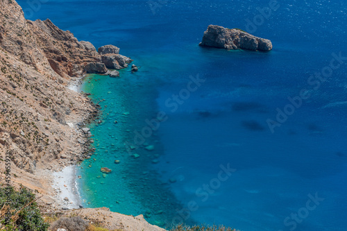 view of the turquise waters from the beach underneeth the famous Hozoviotissa Monastery standing on a rock over the Aegean sea in Amorgos island, Cyclades, Greece.