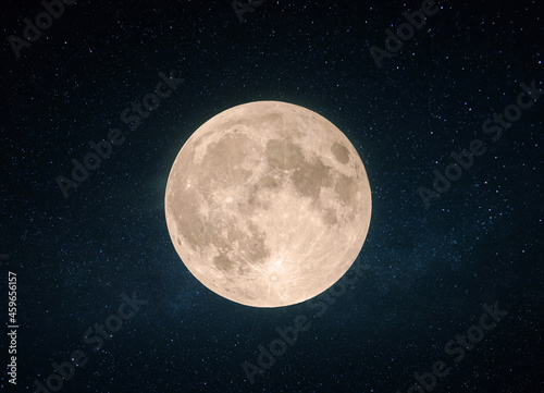 Beautiful yellow full moon with craters in the starry sky.