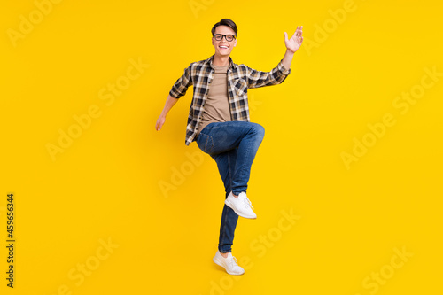 Photo of carefree nice guy raise hand dance wear plaid shirt jeans footwear isolated yellow color background © deagreez