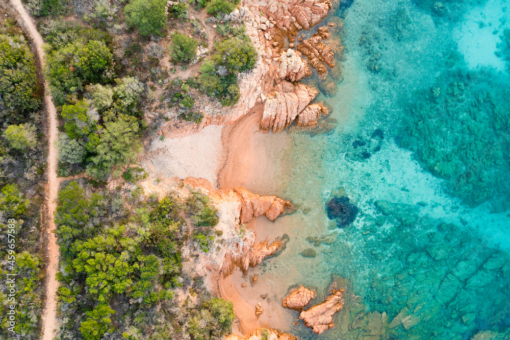 View from above, stunning aerial view of a green and rocky coastline with a white sand beach bathed by a turquoise, crystal clear water. Liscia Ruja, Costa Smeralda, Sardinia, Italy..