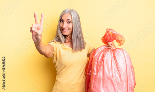 middle age pretty woman smiling and looking happy, gesturing victory or peace. plastic garbaje bag photo