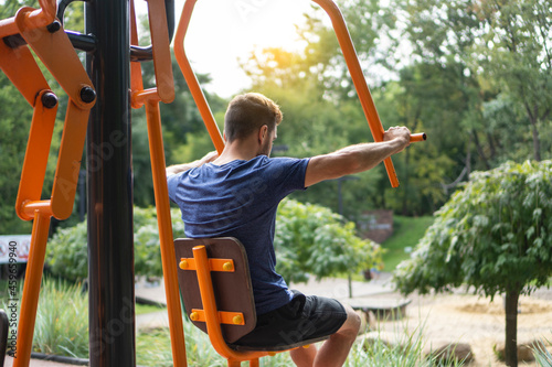 Man trains on the outdoors training apparatus of the open air gym.