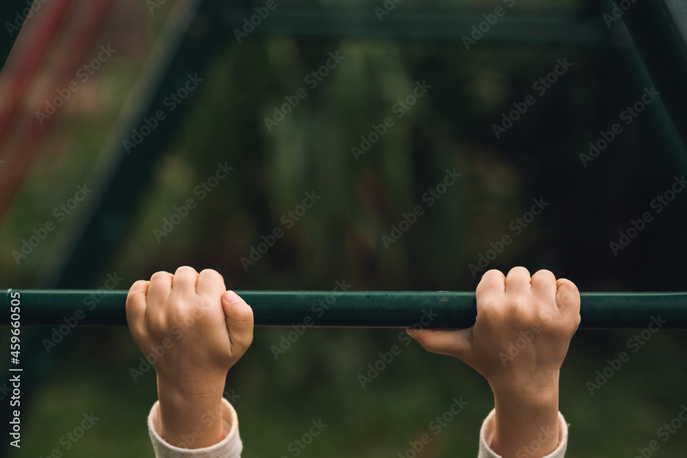 Child on the playground. Hanging on the horizontal bar Child on the playground. Hanging on the horizontal bar