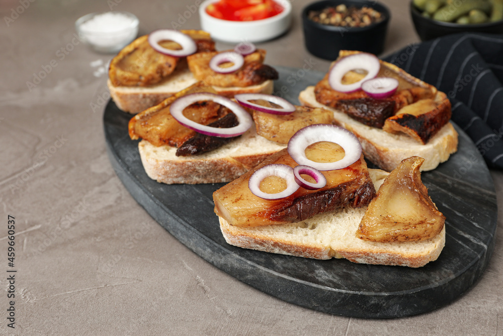 Tasty fried pork lard with bread slices and onion on grey table
