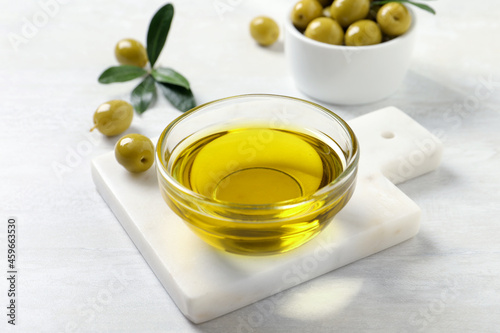 Glass bowl with fresh olive oil on white wooden table