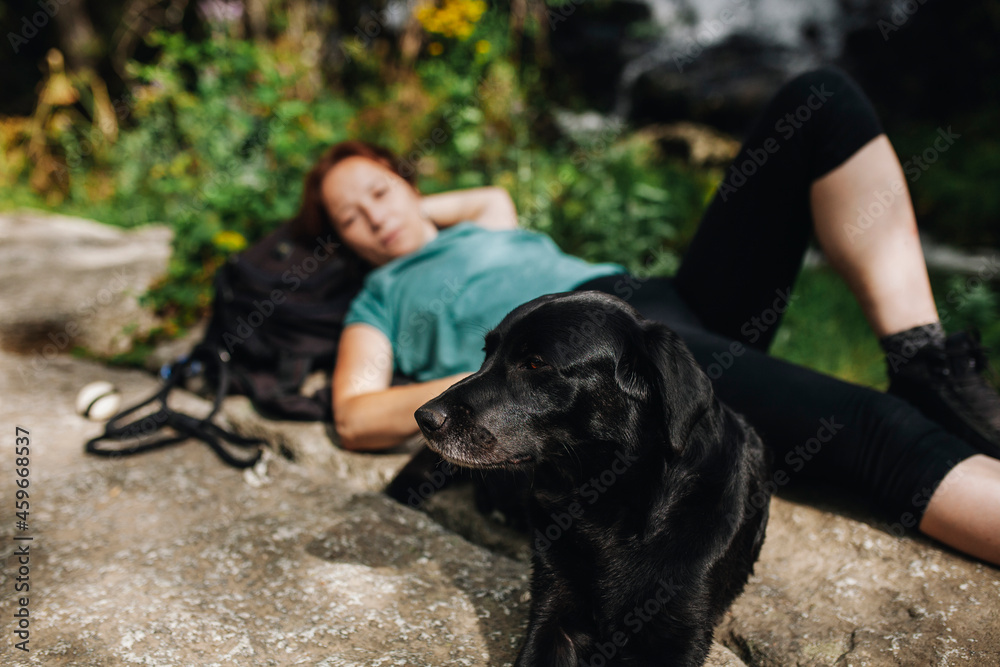 Black dog lying with female pet owner on sunny day Black dog lying with female pet owner on sunny day