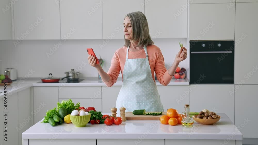 Blogger influencer mature lady hold telephone scroll feed network eat cucumber Blogger influencer mature lady hold telephone scroll feed network eat cucumber
