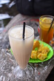 Glass of iced coffee milk on wooden table with blur background. Refreshing food. Milkshake in transparent glass on food background.