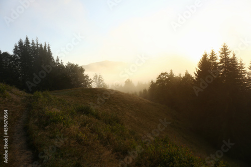 Picturesque view of mountains covered with fog at sunrise