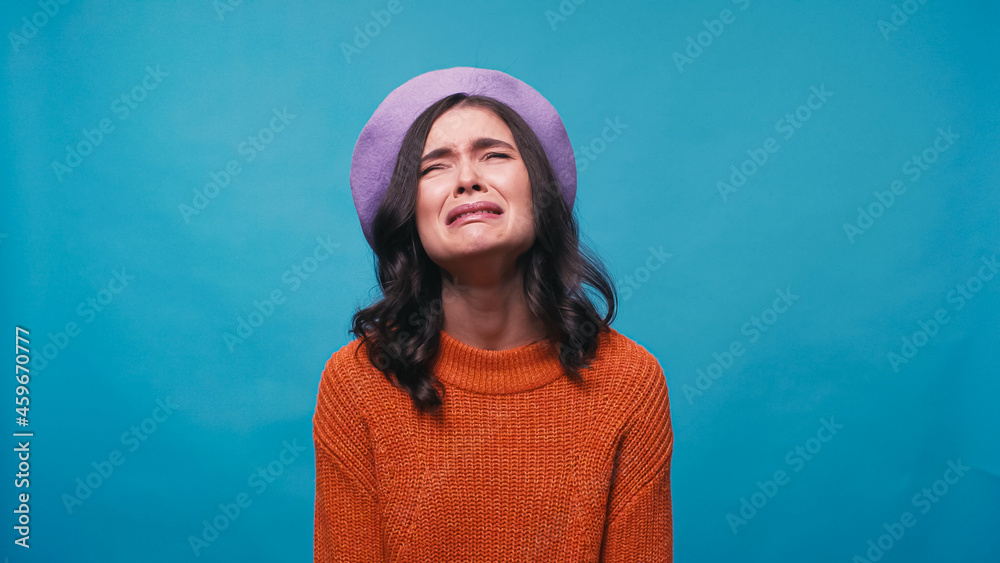 sad woman in warm jumper and beret crying isolated on blue sad woman in warm jumper and beret crying isolated on blue