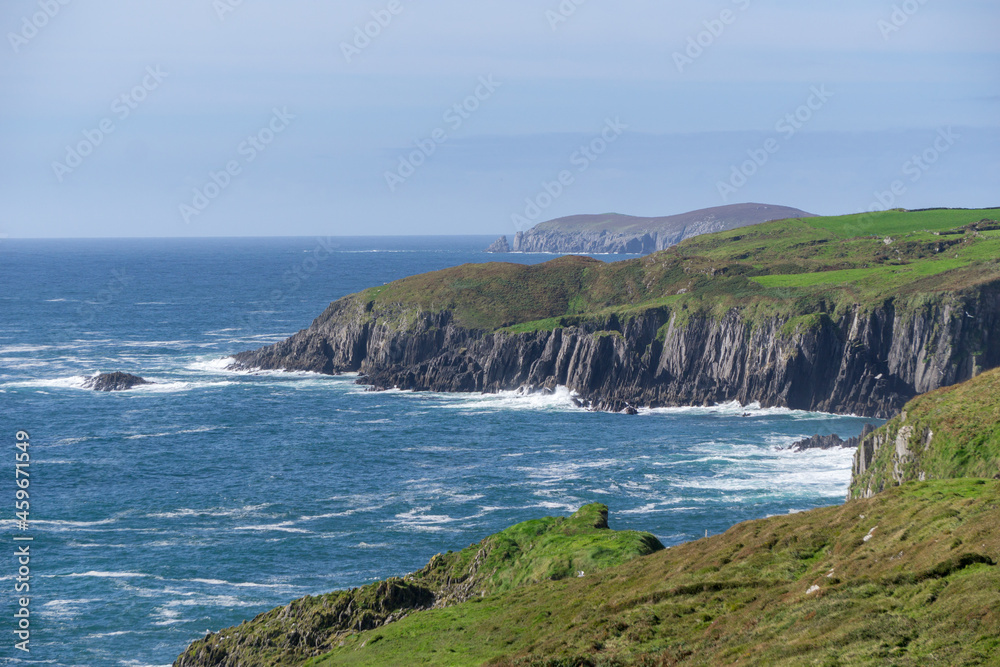 coastline ireland at wild atlantic way during day with some sheep on green grass and steep cliffs