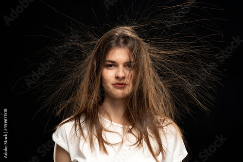 Portrait of woman with static hair up, isolated on black background. 