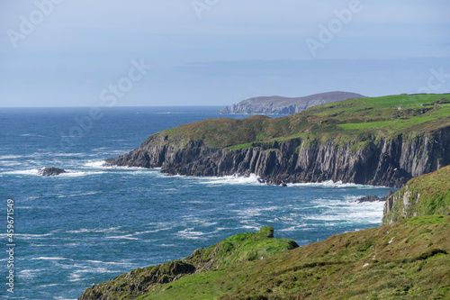 coastline ireland at wild atlantic way during day with some sheep on green grass and steep cliffs