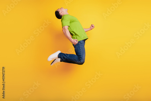 Portrait of crazy astonsihed sportive guy jump have fun on yellow wall