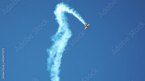 Small retro airplane, light aircraft flying in blue sky and doing stunts