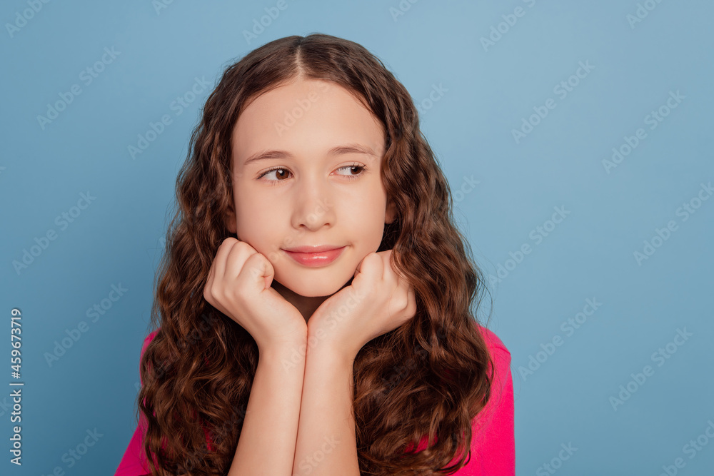 Portrait of sweet interested little girl hands cheeks look blank space think on blue background Portrait of sweet interested little girl hands cheeks look blank space think on blue background
