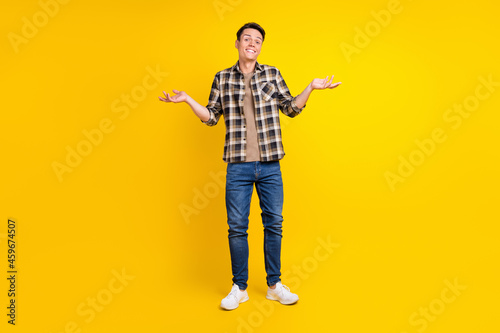 Photo of clueless uncertain guy shrug shoulders wear plaid shirt jeans shoes isolated yellow color background