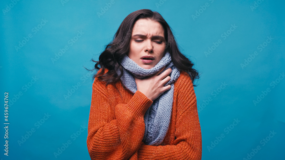 ill woman in warm scarf touching neck while suffering from pain in throat isolated on blue ill woman in warm scarf touching neck while suffering from pain in throat isolated on blue